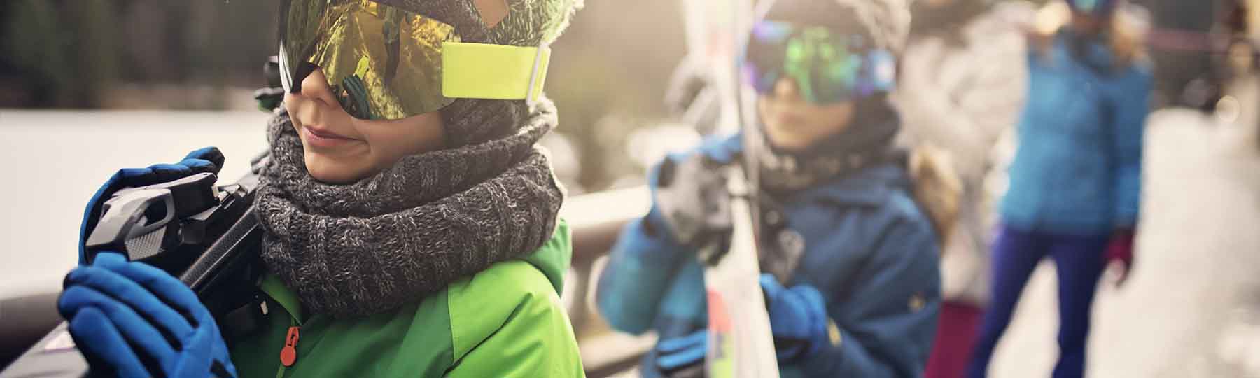 Family carrying skis to ski slope in ski resort. Sunny winter day. Nikon D850